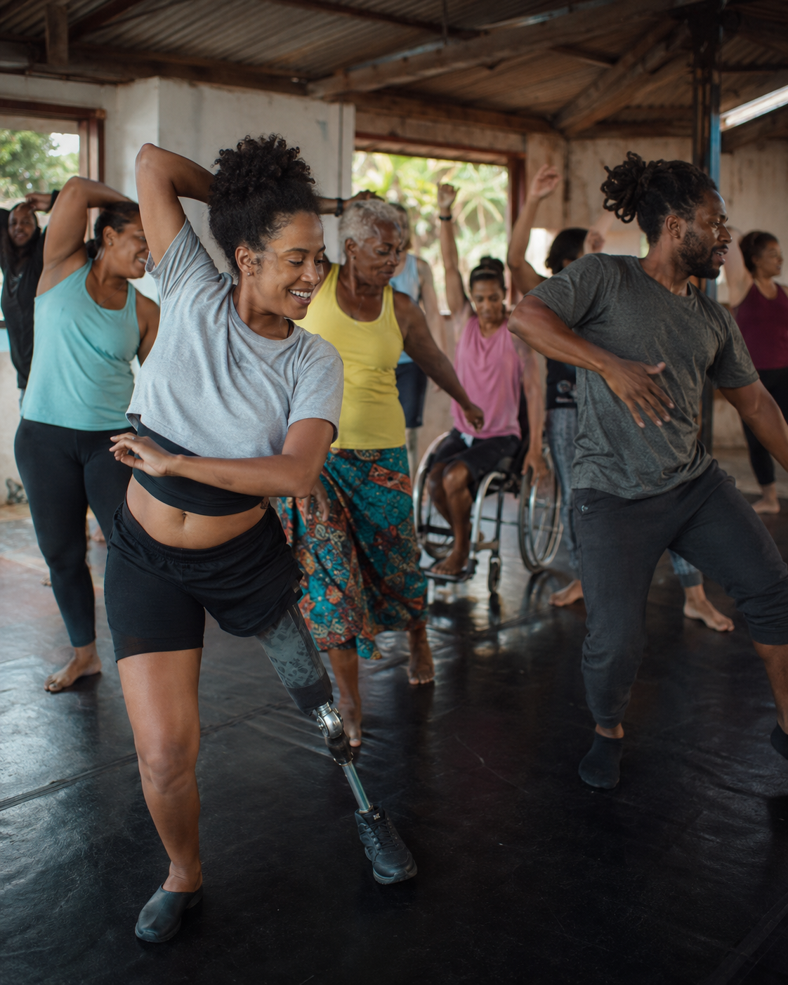 Grupo diverso dança em espaço aberto: participantes de diferentes idades e corpos, incluindo pessoa com prótese e pessoa em cadeira de rodas.